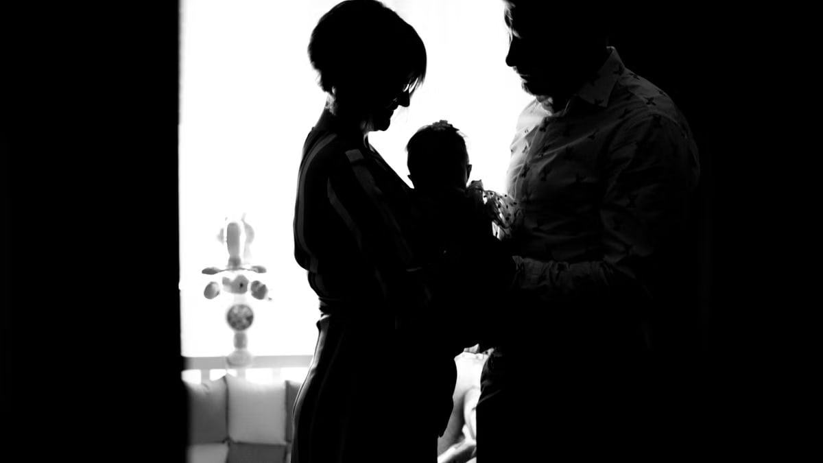 Heartwarming silhouette of parents holding their baby in a black and white setting.